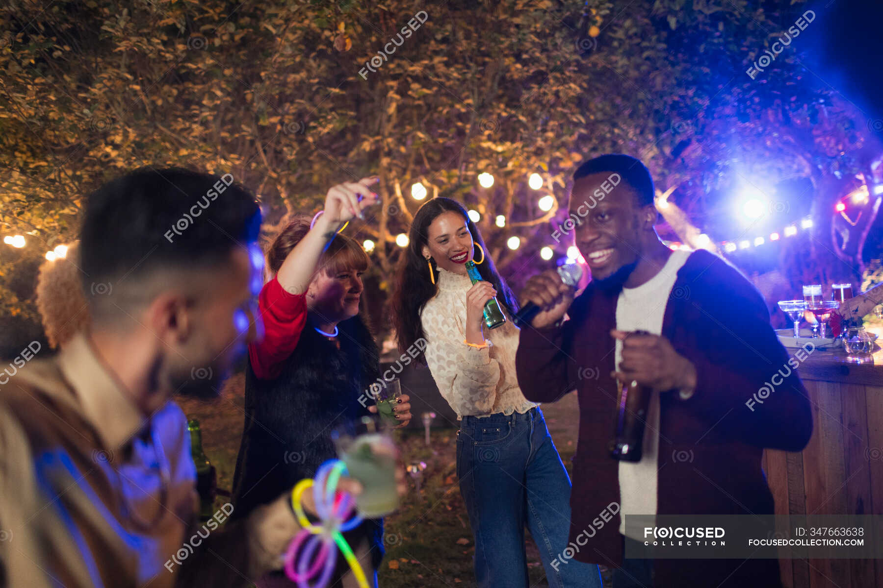 Friends dancing and singing karaoke at garden party — Young Men