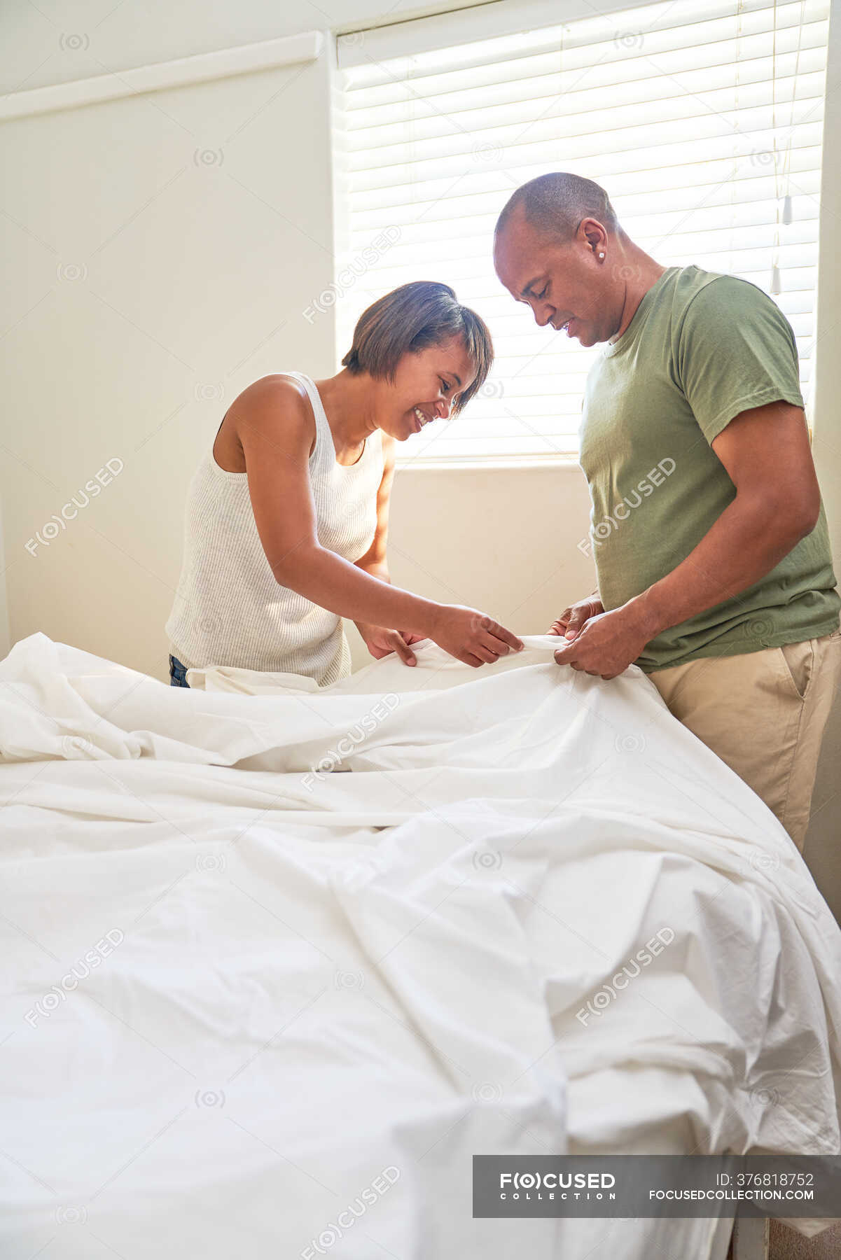 couple-making-bed-together-in-bedroom-make-black-man-stock-photo