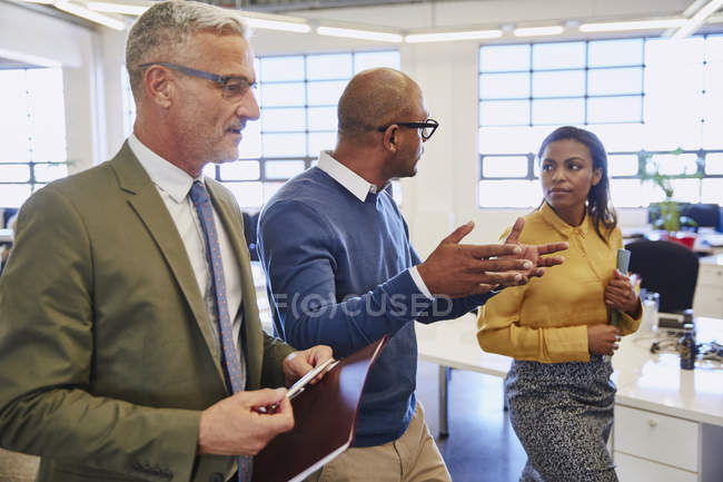 Gente de negocios caminando y hablando en la oficina - foto de stock