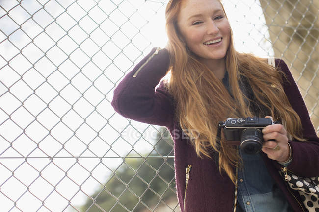 Счастливая молодая женщина с фотоаппаратом на улице — стоковое фото