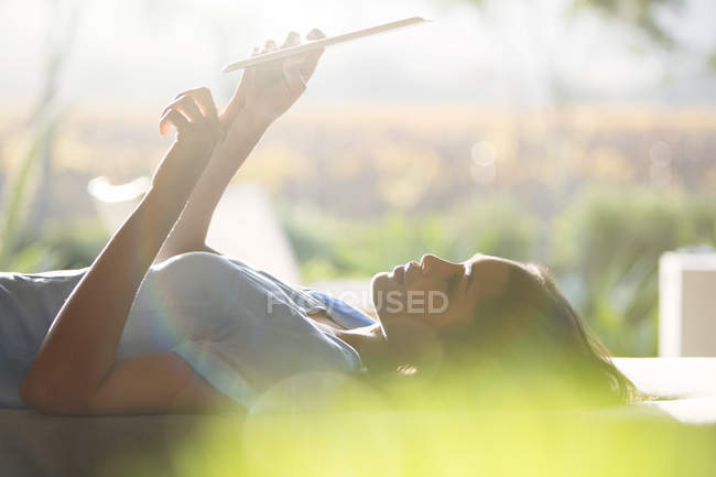 Woman laying and using digital tablet on patio — Stock Photo