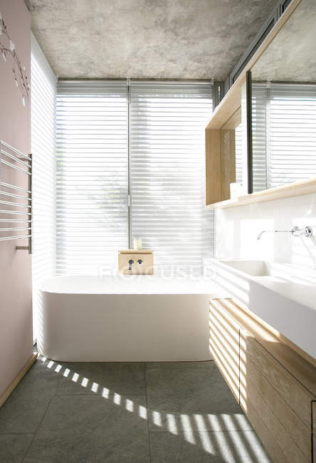 Світло крізь жалюзі за ванною в сучасній ванній — стокове фото