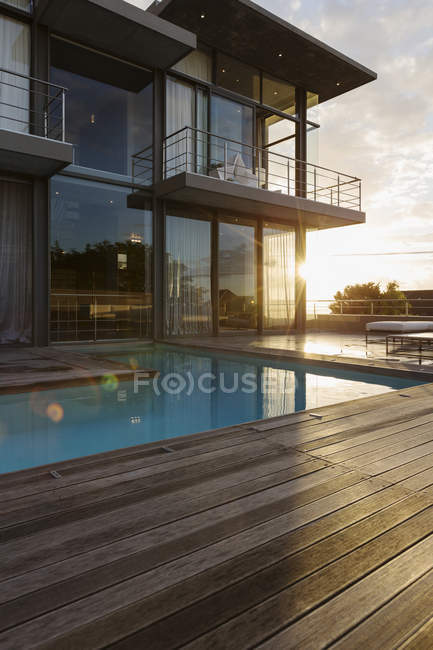 Soleil derrière maison de luxe avec piscine — Photo de stock
