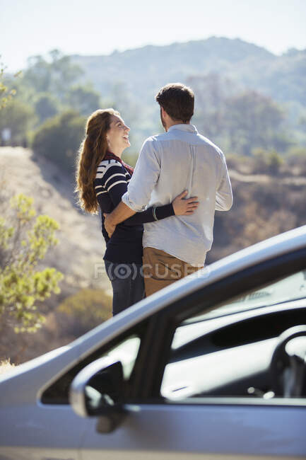 Щаслива пара обіймається на узбіччі поза машиною — стокове фото