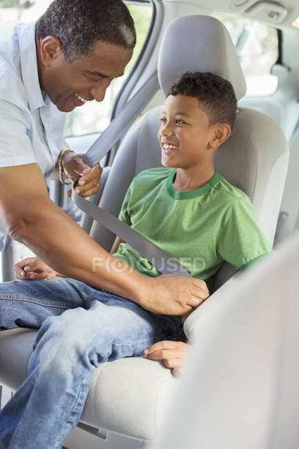 Grandfather fastening grandson?s seat belt in back seat of car — Stock Photo