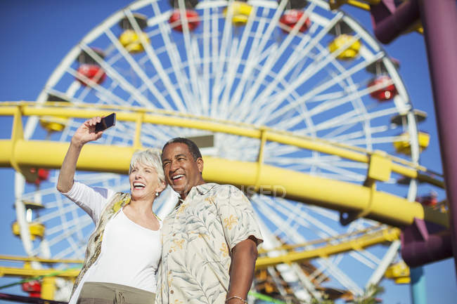 Couple sénior enthousiaste prenant selfie au parc d'attractions — Photo de stock