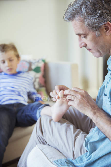 Father bandaging son's toe — Stock Photo