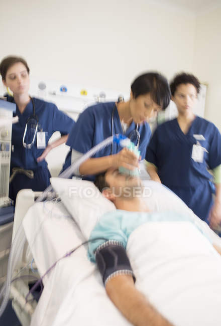 Team di medici che somministrano ossigeno al paziente in unità di terapia intensiva — Foto stock