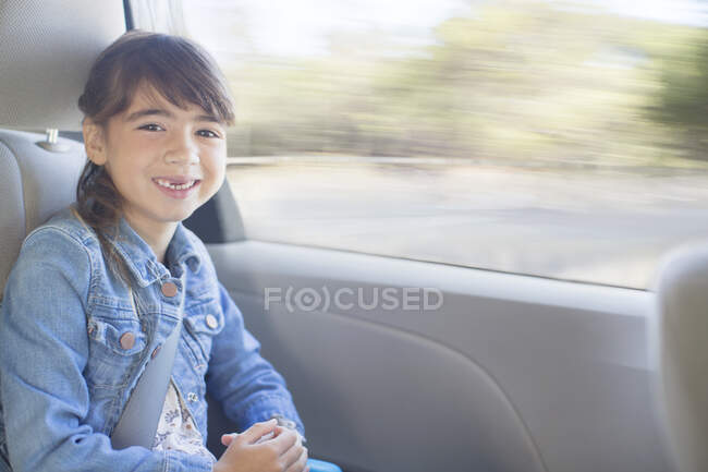 Portrait of happy girl in back seat of car — Stock Photo