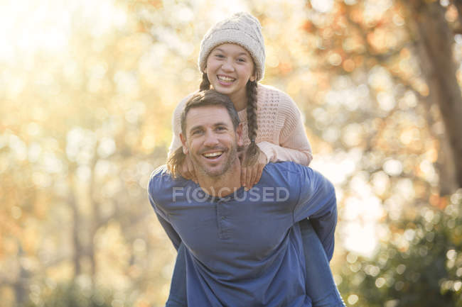 Portrait enthusiastic father piggybacking daughter outdoors — Stock Photo