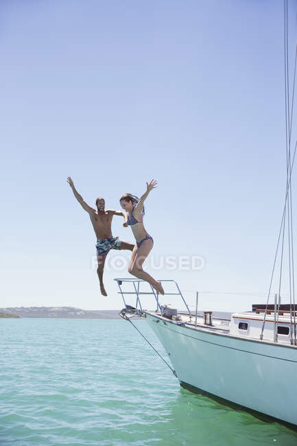 Casal saltando do barco para a água — Fotografia de Stock