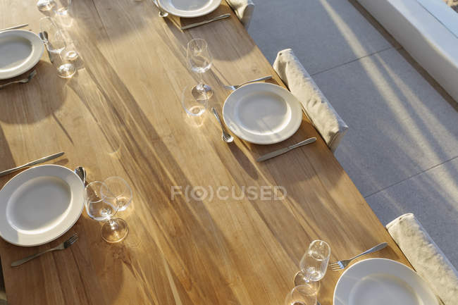 Placesettings en la mesa soleada patio de madera - foto de stock