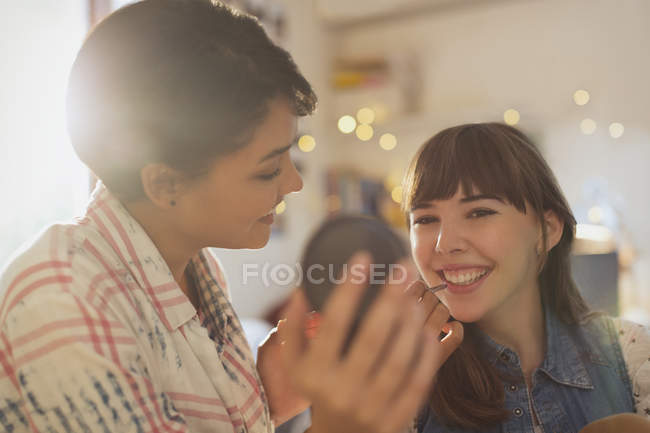 Mujeres jóvenes amigas aplicando maquillaje - foto de stock