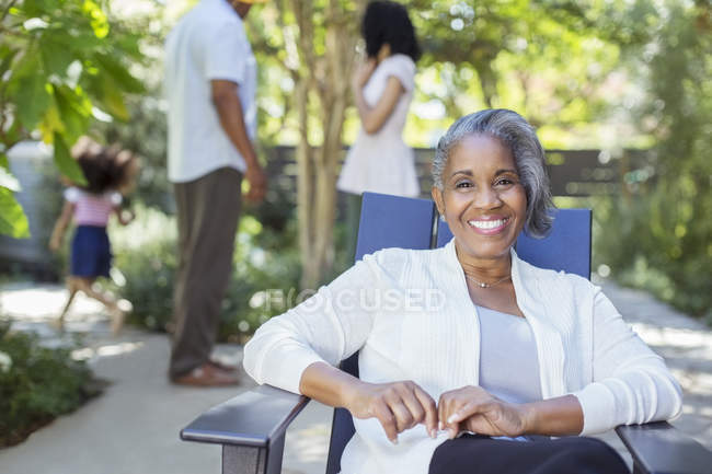 Portrait of smiling senior woman on patio with family in background — Stock Photo