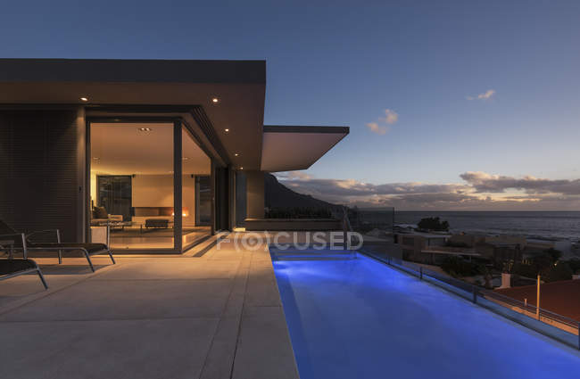 Ruhige blaue Runde Schwimmbad außerhalb moderner Luxus-Haus Schaufenster außen in der Dämmerung — Stockfoto