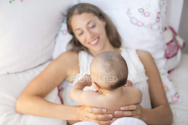 Mutter hält Baby von oben auf Bett — Stockfoto