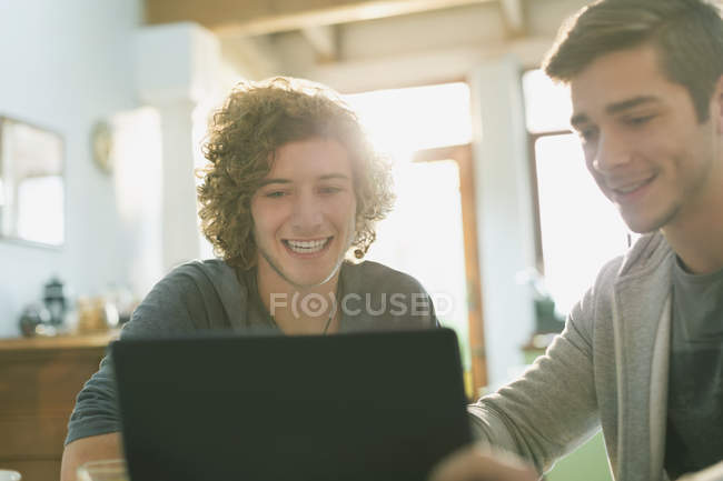 Sonriendo a los jóvenes estudiantes universitarios que estudian con el ordenador portátil - foto de stock