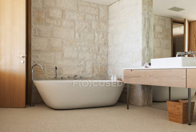 Parede de pedra atrás da banheira de imersão no banheiro moderno — Fotografia de Stock