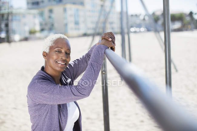 Retrato de mulher confiante apoiando-se no bar no parque infantil da praia — Fotografia de Stock