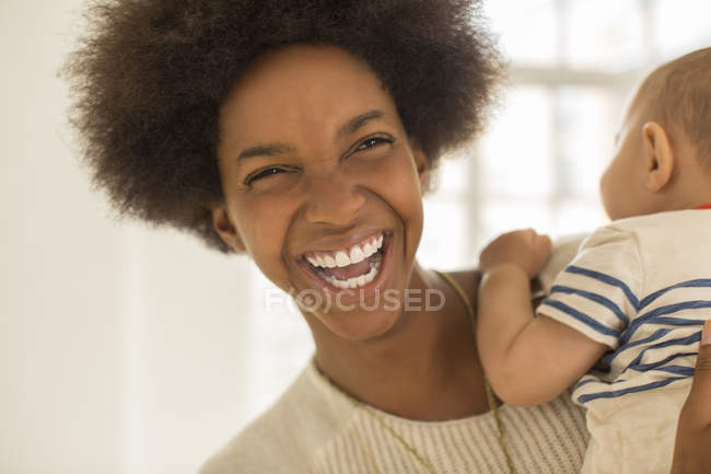 Rindo mãe segurando bebê menino em casa — Fotografia de Stock