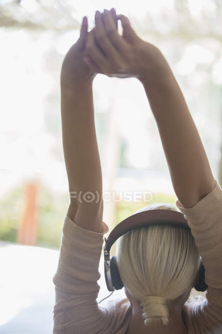 Mujer estirándose en auriculares - foto de stock