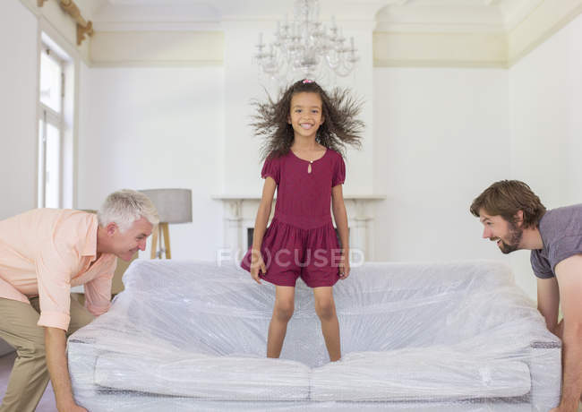 Family lifting couch with young girl standing on top — Stock Photo