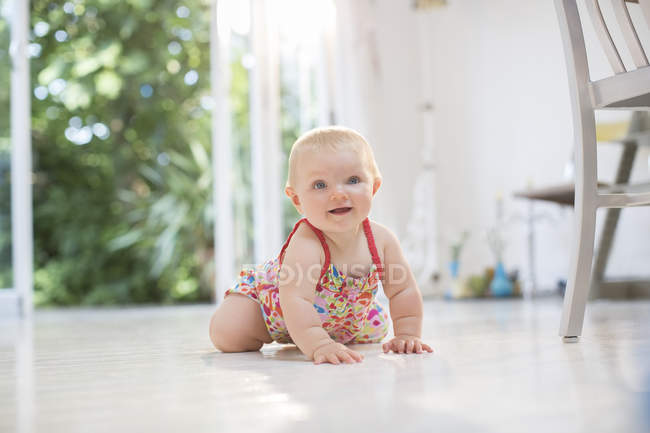 Baby girl crawling on kitchen floor — Stock Photo