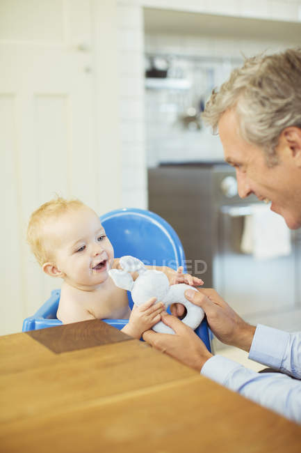 Father playing with baby in high chair — Stock Photo