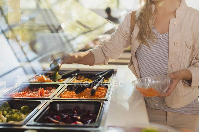 Young woman at salad bar in grocery store market — Stock Photo