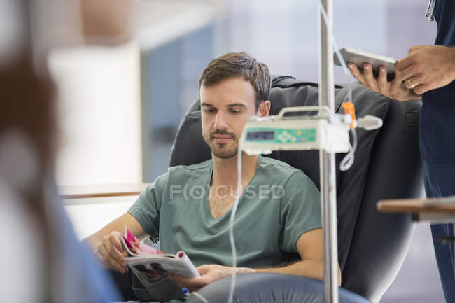 Patient reading magazine, undergoing medical treatment in outpatient clinic — Stock Photo
