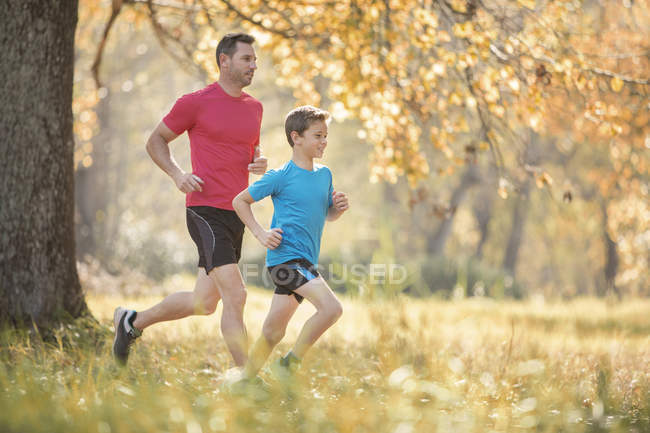 Father and son jogging in autumn park — Stock Photo