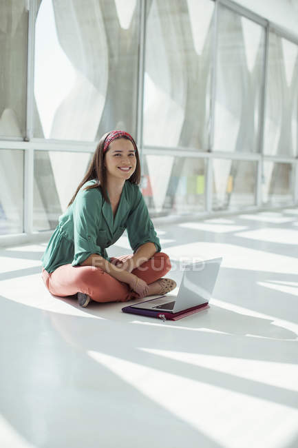 Портрет впевненої випадкової бізнес-леді, що використовує ноутбук на підлозі в сонячному офісі — стокове фото