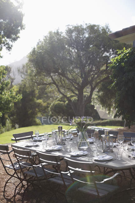 Place settings on sunny rural patio table — Stock Photo
