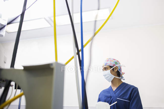 Jovem enfermeira controlando equipamentos médicos durante a cirurgia — Fotografia de Stock