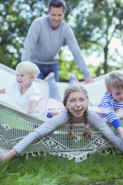 Father pushing children in hammock outdoors — Stock Photo