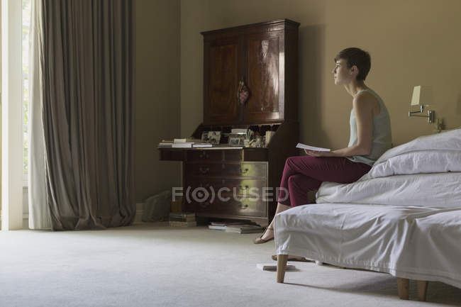 Jovem mulher sentada na cama com tablet digital nas mãos — Fotografia de Stock