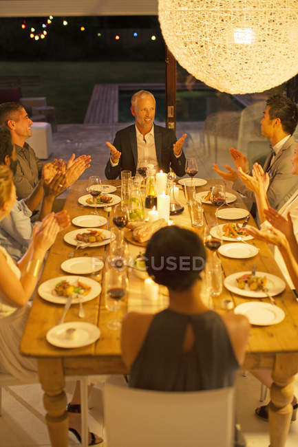 Друзья аплодируют человеку за ужином — стоковое фото