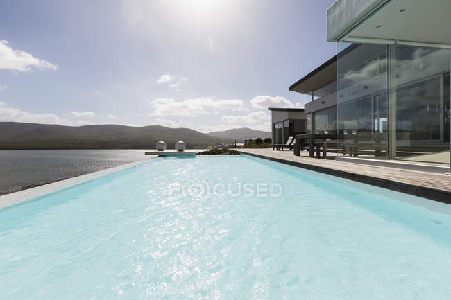 Sunny tranquila casa de lujo moderna escaparate exterior con piscina infinita y vista al mar - foto de stock