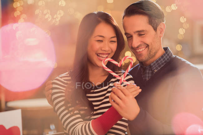 Couple holding heart-shape candy canes — Stock Photo