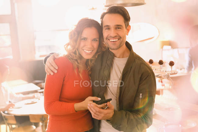 Portrait affectionate smiling couple using cell phone in bar — Stock Photo
