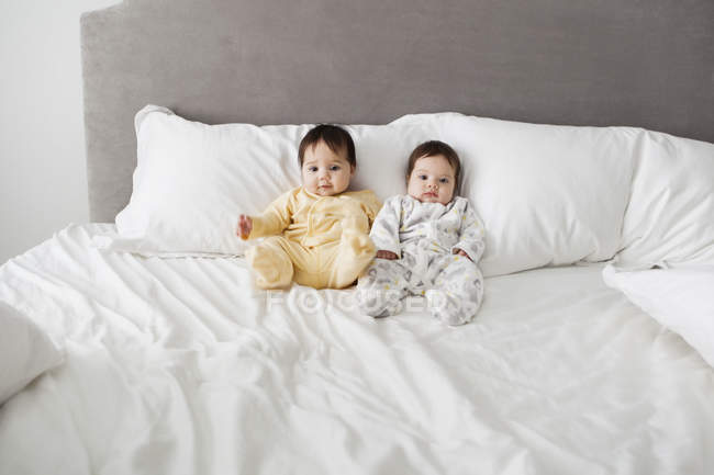 Дівчаток-близнюків чарівні дитини, сидячи на ліжку — стокове фото