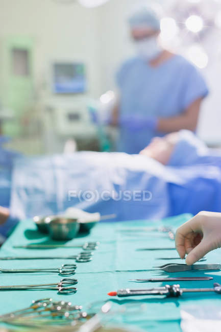 Krankenschwester arrangiert chirurgische Instrumente auf Tablett im Operationssaal — Stockfoto