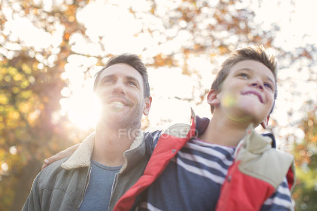 Padre in figlio sotto soleggiato albero autunnale — Foto stock