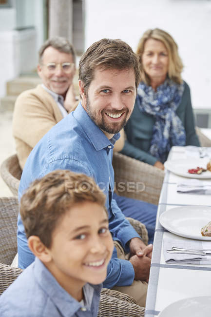 Портрет усміхненої багатоповерхової сім'ї, що насолоджується обідом з патіо — стокове фото