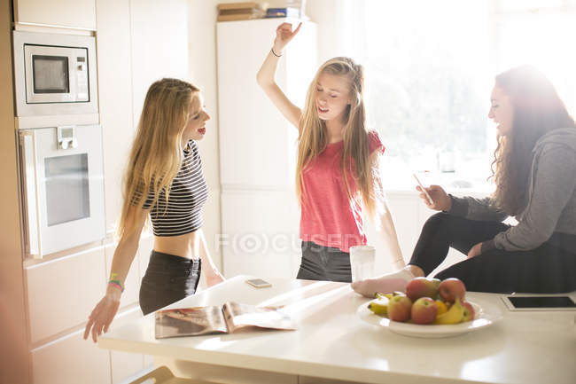 Teenage girls dancing in sunny kitchen — Stock Photo