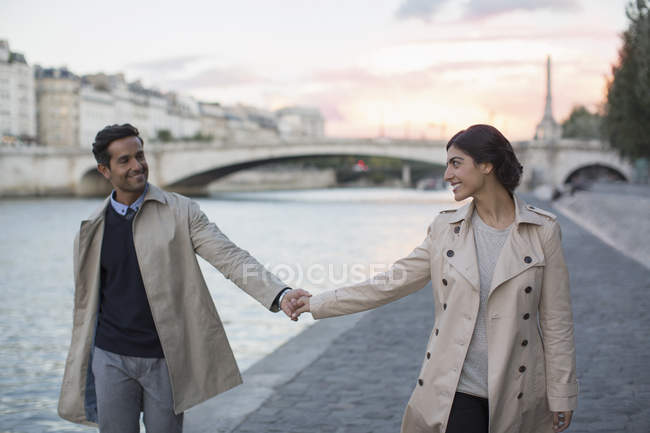 Couple holding hands along Seine River, Paris, France — Stock Photo