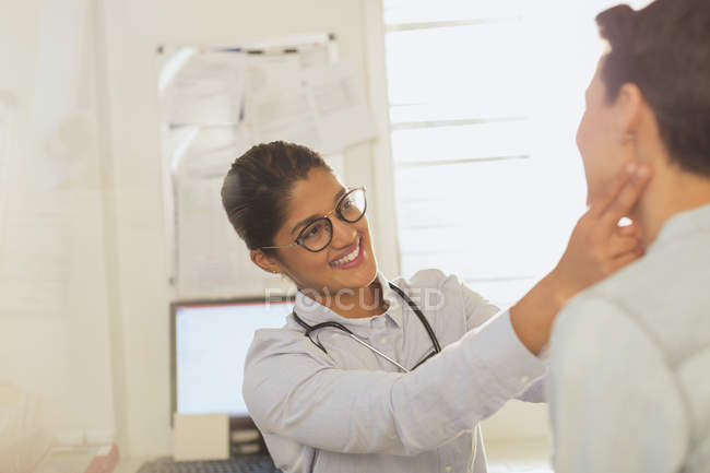 Жінка-лікар перевіряє шийні лімфатичні вузли залози пацієнта в кабінеті обстеження — стокове фото