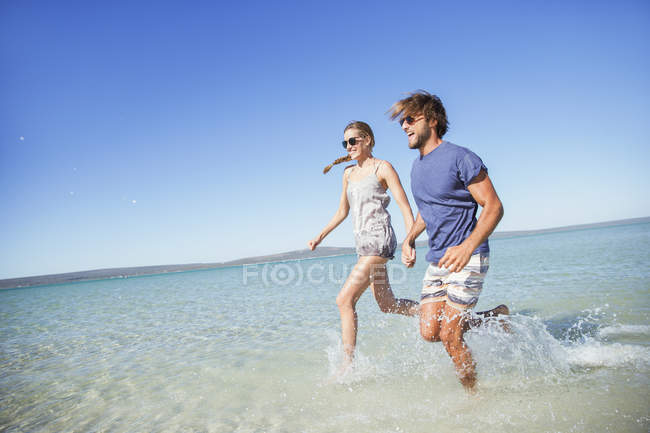 Casal correndo na água juntos — Fotografia de Stock
