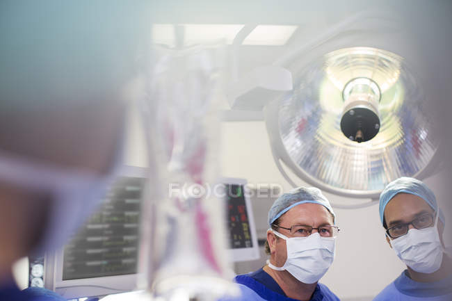 Two surgeons looking at saline bag during surgery — Stock Photo
