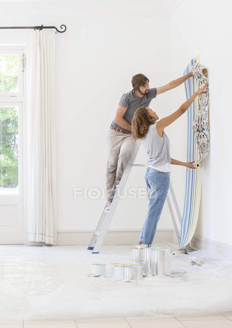Casal pendurado papel de parede juntos — Fotografia de Stock